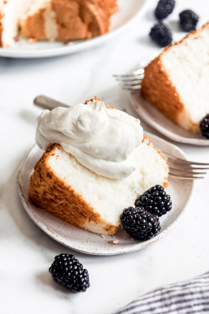 A slice of angel food cake with whipped cream and blackberries.