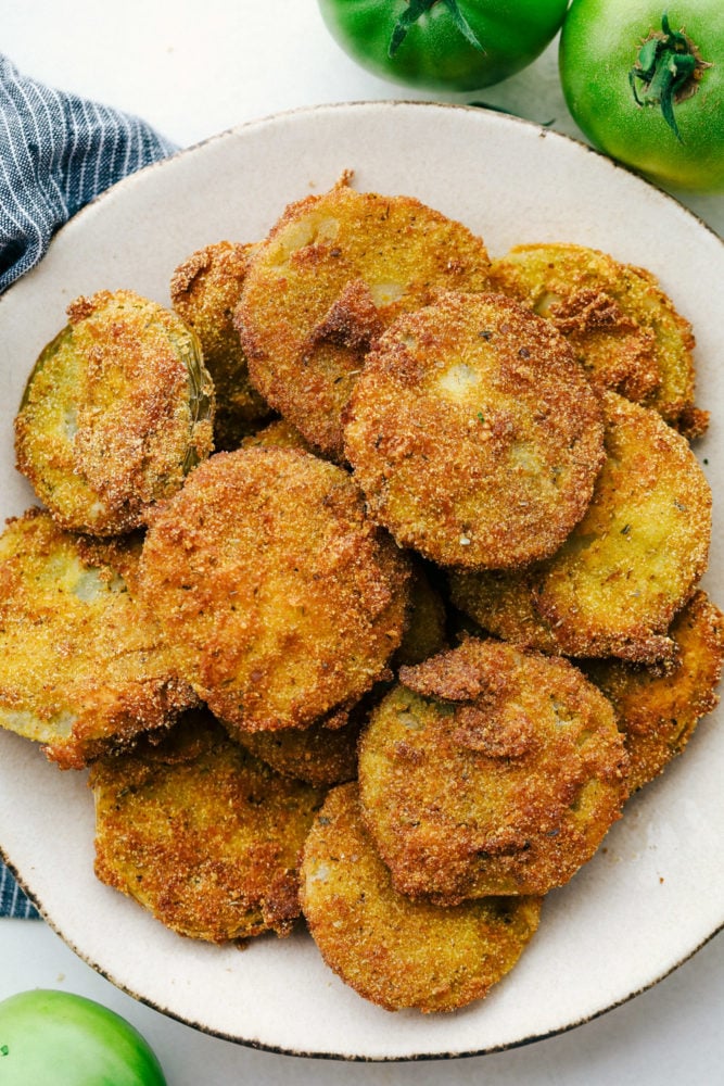 Fried green tomatoes stacked on a white plate.