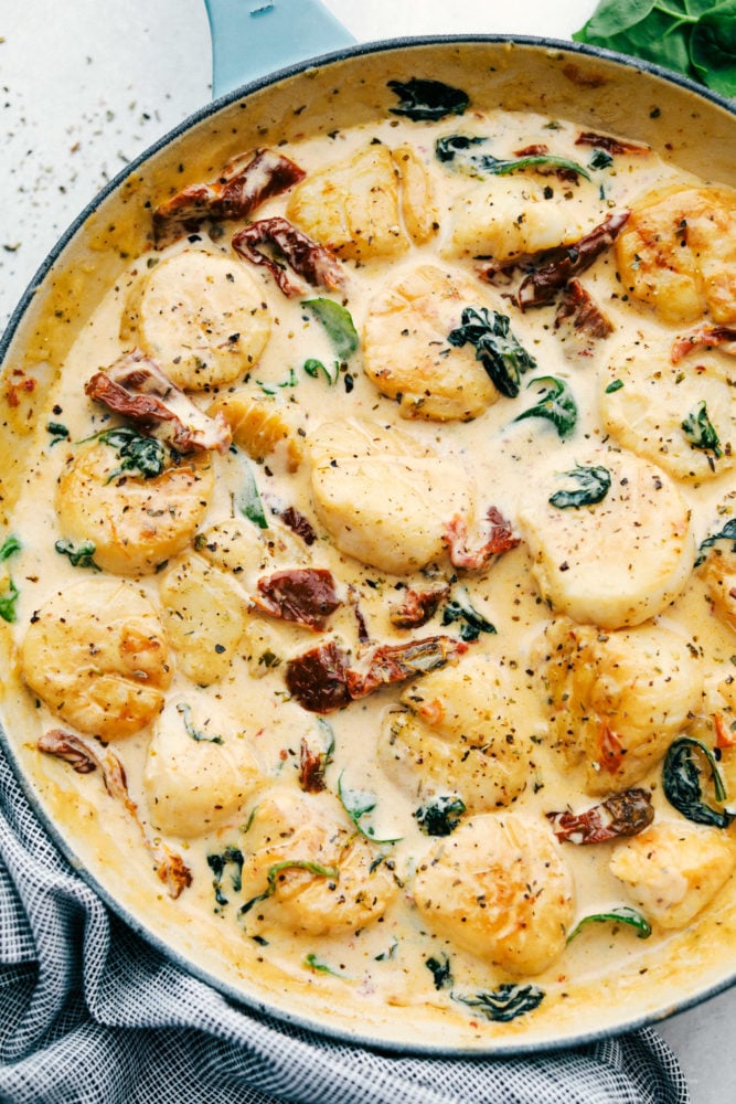 Creamy tuscan garlic scallops in a skillet.