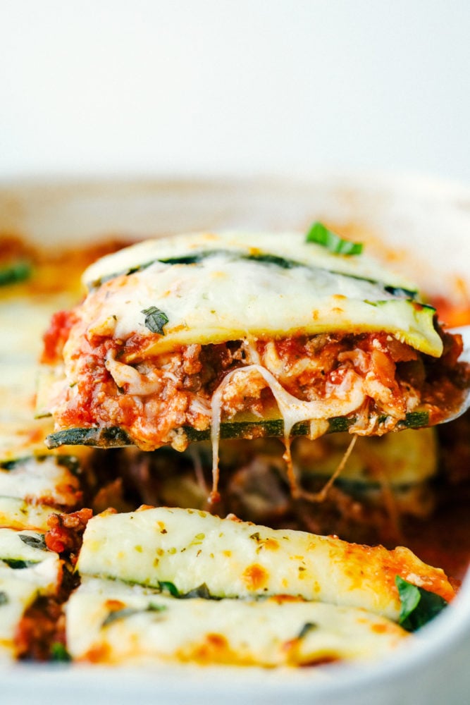 A photo of zucchini lasagna having a piece taken out of the casserole dish. 