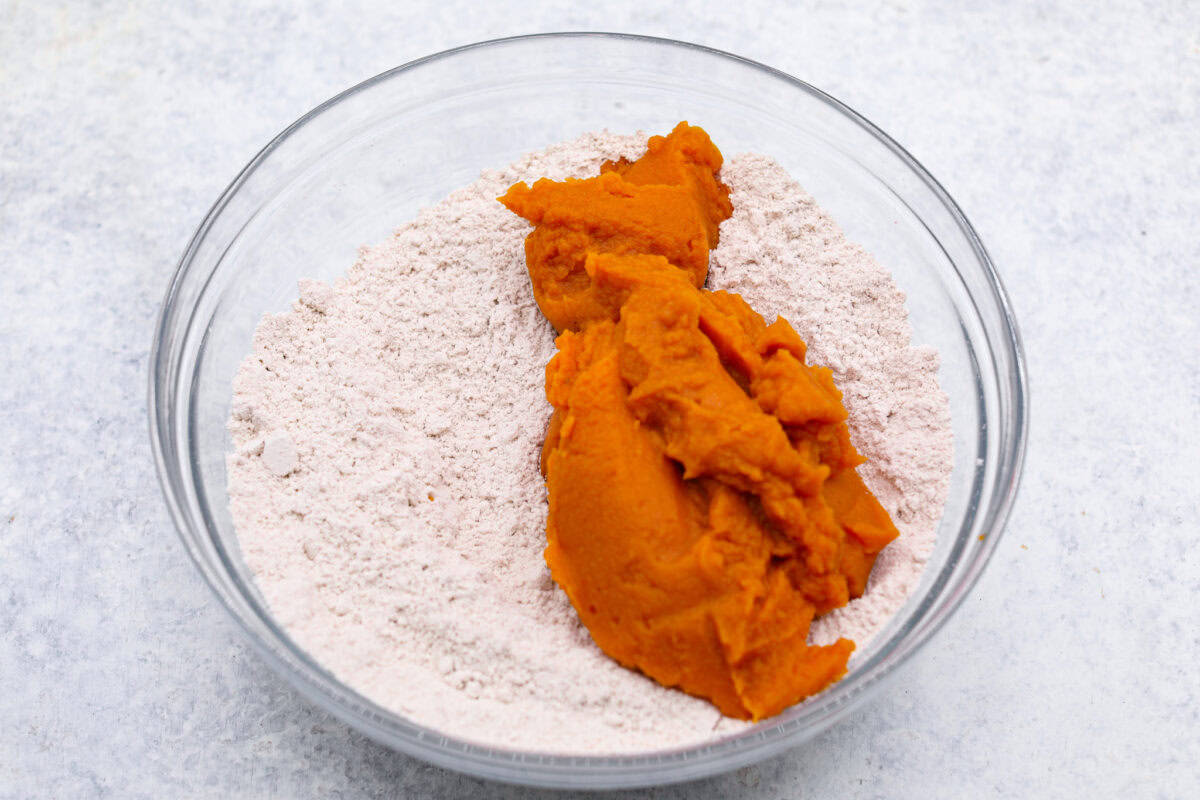 Overhead shot of pumpkin puree with spiced cake mix in a glass bowl. 