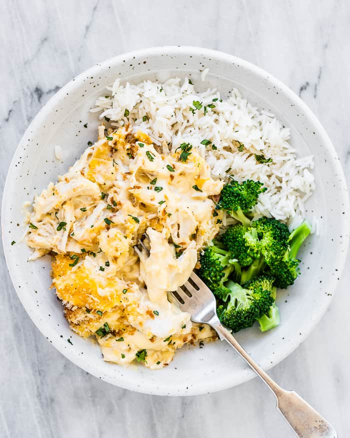 Eine weiße Schüssel mit Hühnerdiwan mit Brokkoli und Reis als Beilage.