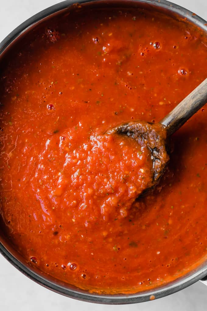 Tomato sauce and wooden spoon in a pan. 