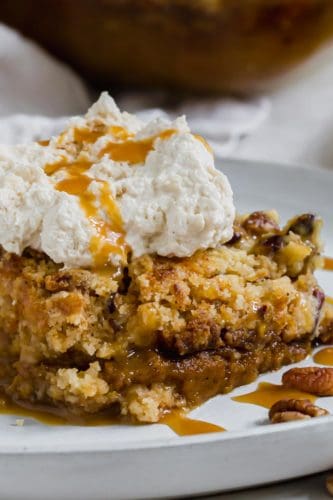 Slice of pumpkin dump cake with whipped cream and caramel sauce drizzled on top.
