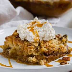 Pumpkin dump cake topped with whipped cream and caramel sauce.