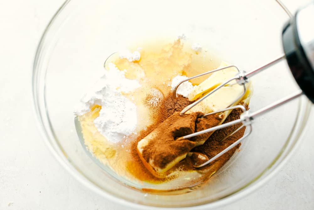 Mixing together cinnamon honey butter in a glass bowl with a mixer. 