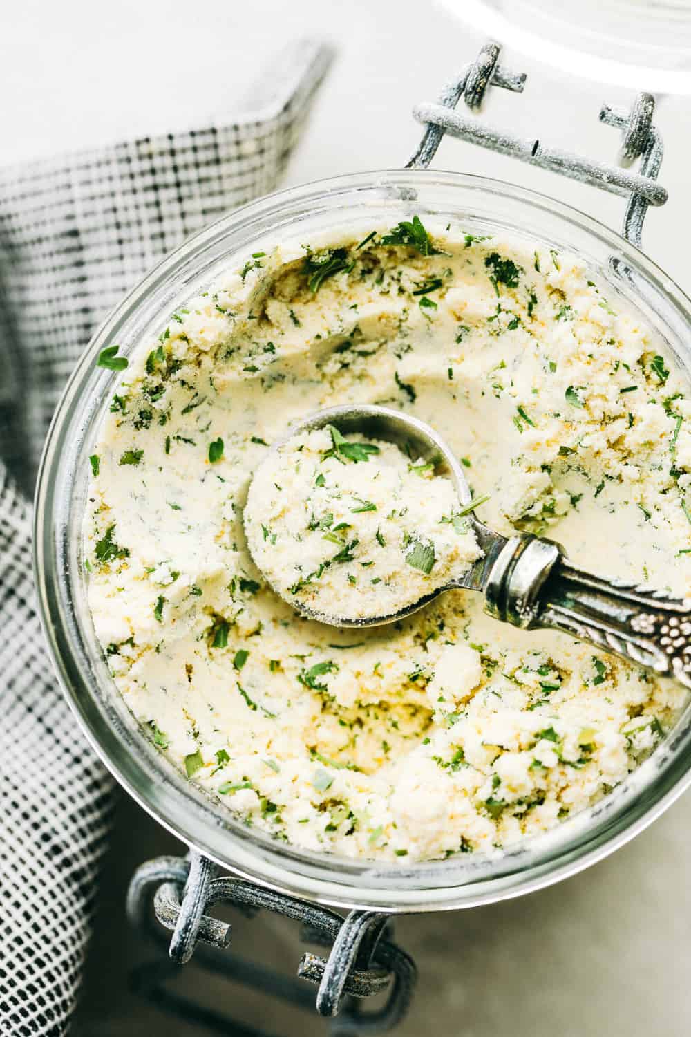 Homemade Ranch Seasoning mix in a jar with a tablespoon lifting up some of the ranch dressing mix. 