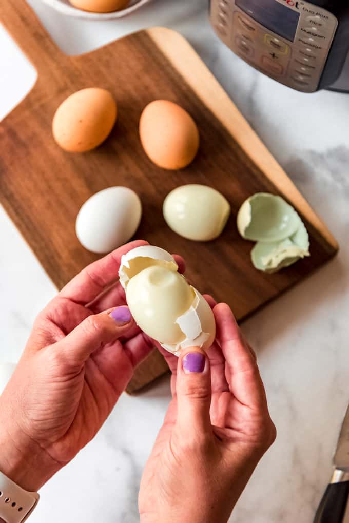 Hände halten ein geschältes hartgekochtes Ei.