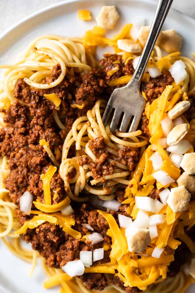 Cincinnati chili with spaghetti noodles garnished with cheese, onions and crackers. 