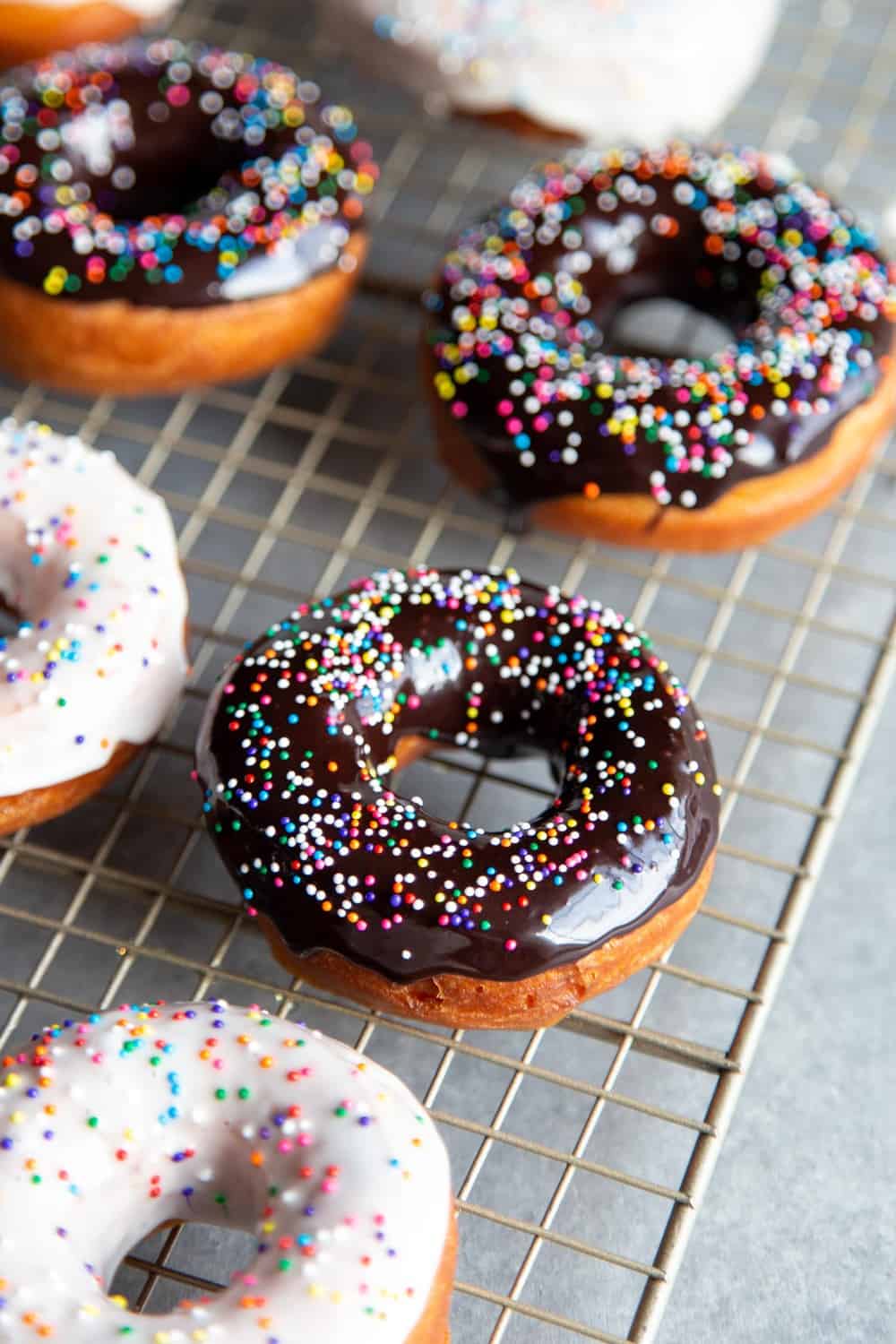 Glazed donuts with sprinkles on a wire rack