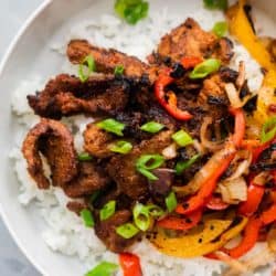 Korean Beef Bulgogi served over rice in a bowl with grilled onions and bell peppers