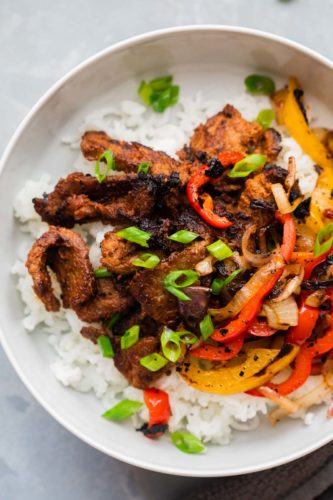 Korean Beef Bulgogi served over rice in a bowl with grilled onions and bell peppers
