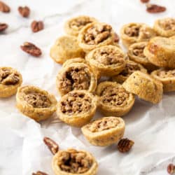 A pile of pecan tassies on a sheet of baking paper