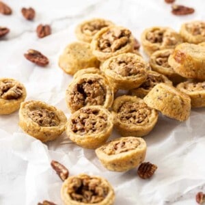A pile of pecan tassies on a sheet of baking paper