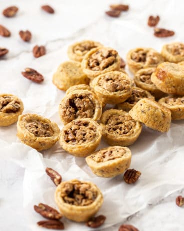 A pile of pecan tassies on a sheet of baking paper