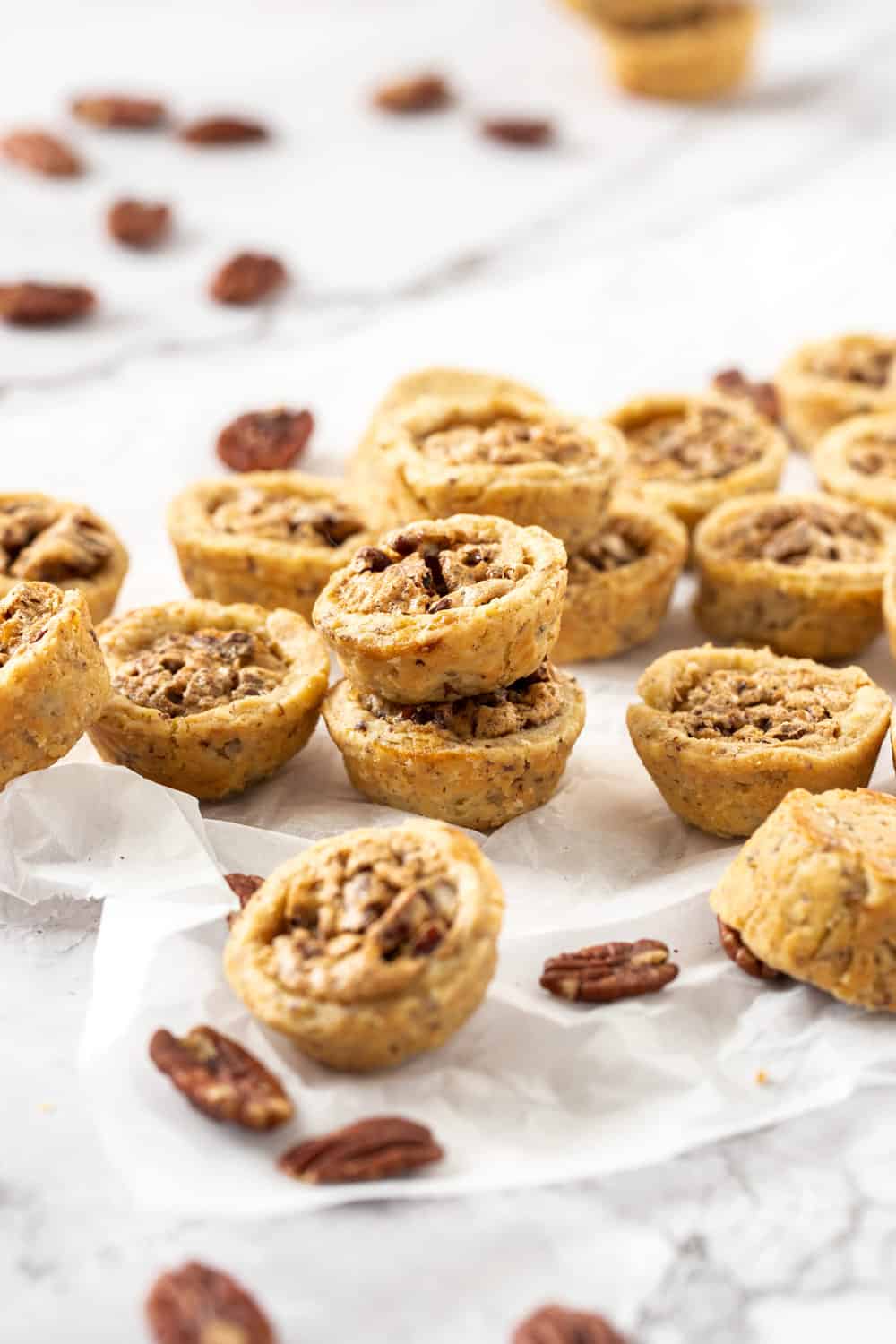 A pile of pecan tassies on a sheet of baking paper