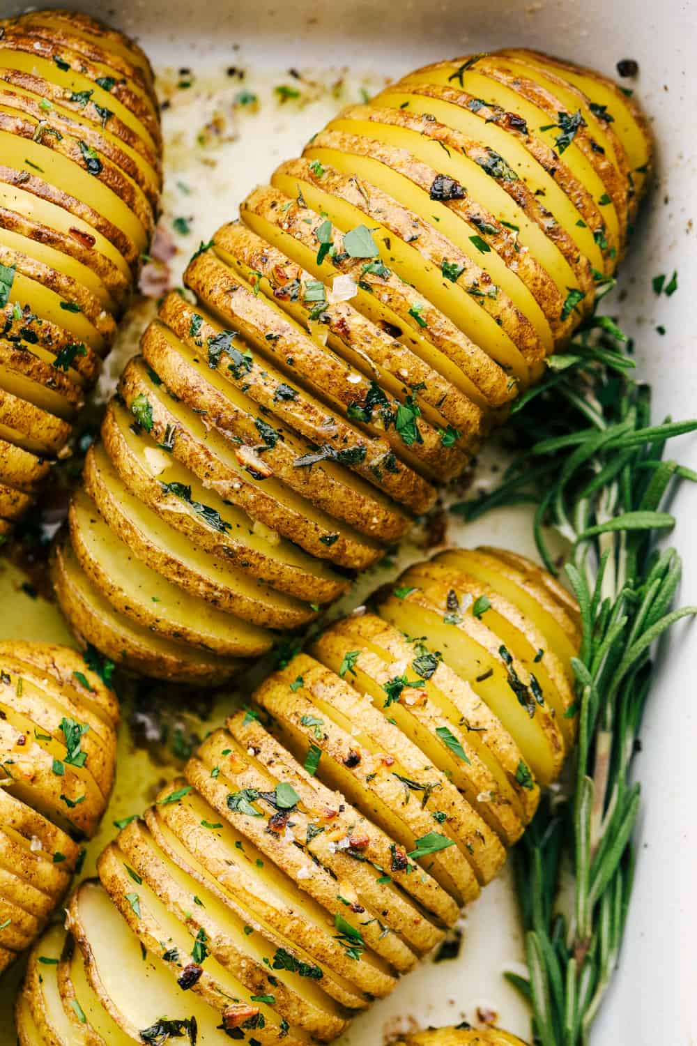 Patatas Hasselback, crujientes y perfectamente condimentadas en un plato blanco.