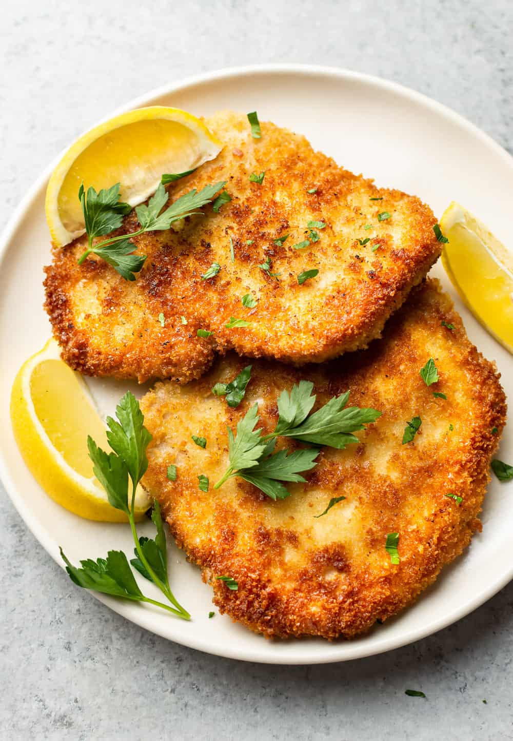 pork schnitzels on a plate with lemon wedges