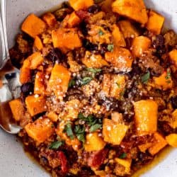 Sweet potato chili in a large bowl topped with parmesan cheese and parsley.
