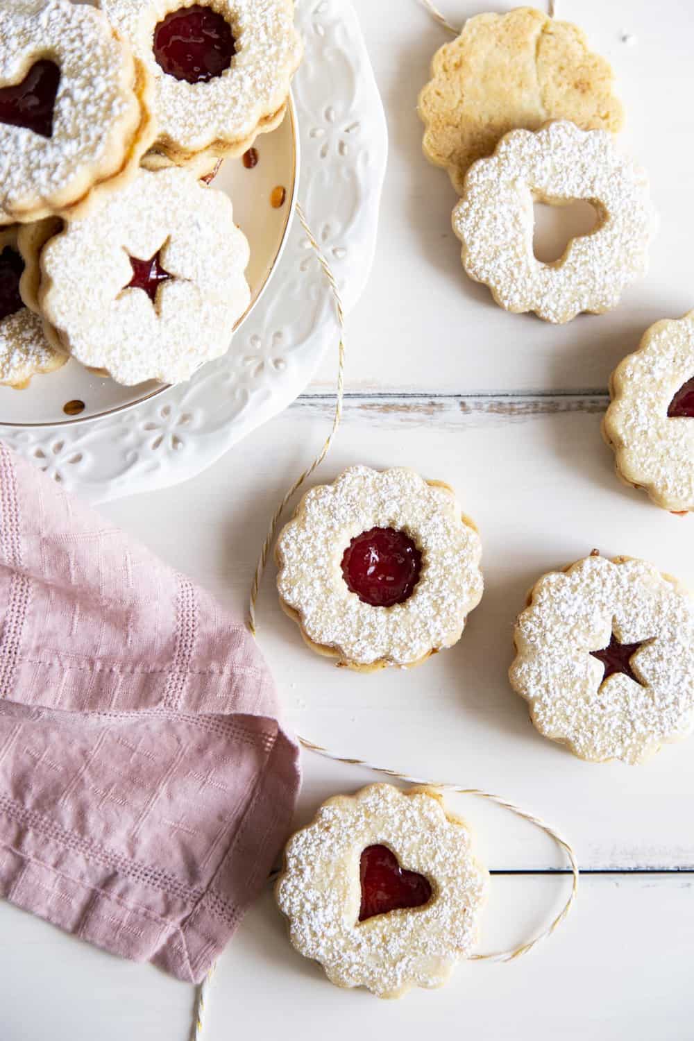Linzer Cookies stacked and laid out in the photo. 