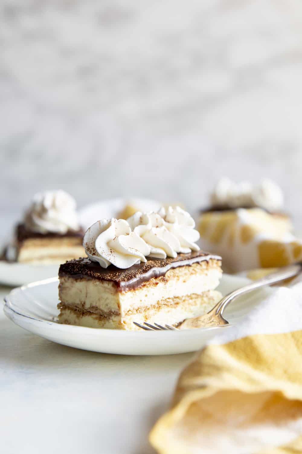 Chocolate eclair slice of cake on a white plate with fork. 