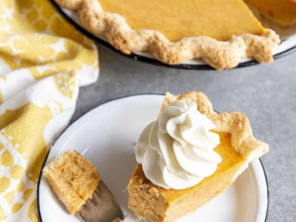 Partial eaten slice of sweet potato pie on a plate next to the pie dish