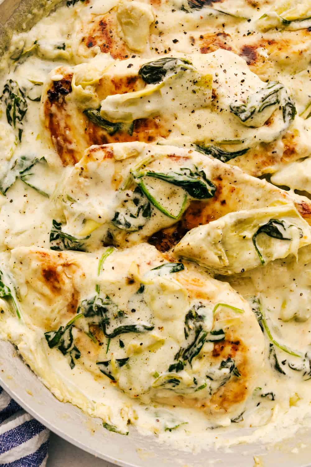 Saucy spinach artichoke chicken on a plate.