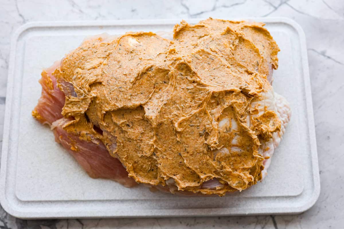 Slow Cooker Turkey Breast is the perfect way to get tender, juicy turkey with a fraction of the prep but all the flavor. Let the slow cooker do ALL the work! Overhead shot of turkey breast covered in the herbed butter mixture.