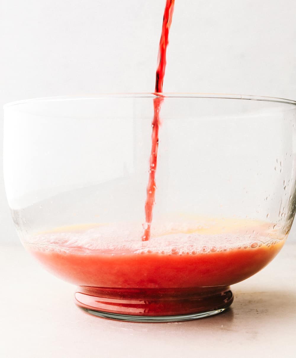 Juice being poured into a glass punch bowl.