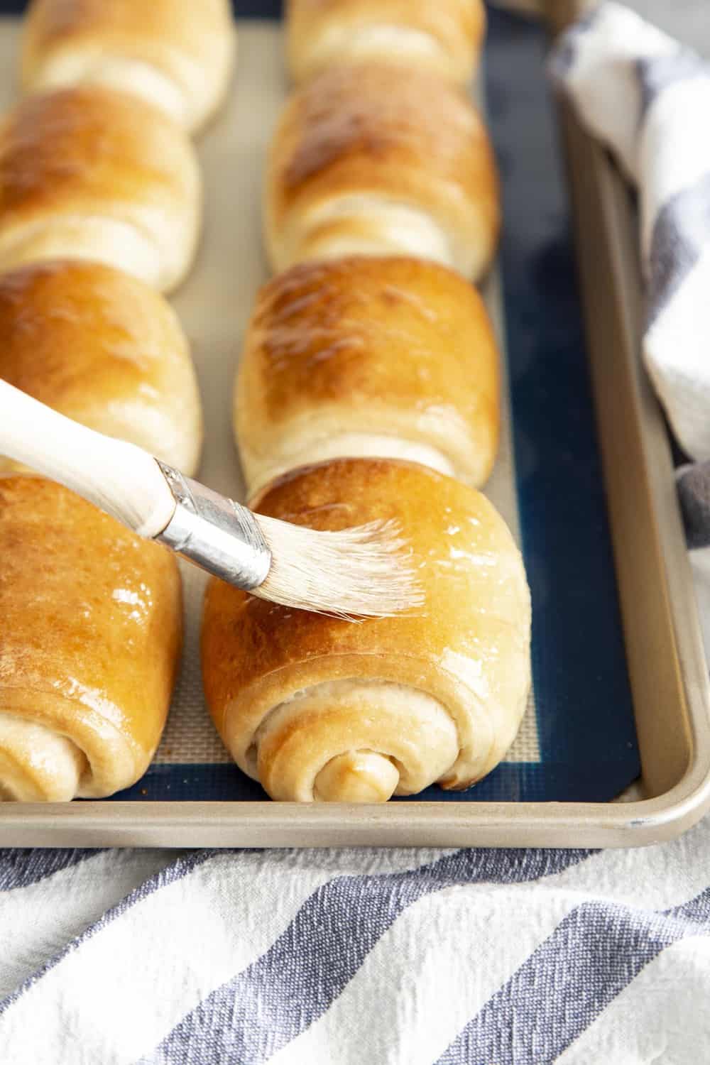 Brushing melted butter on a baked lion house roll