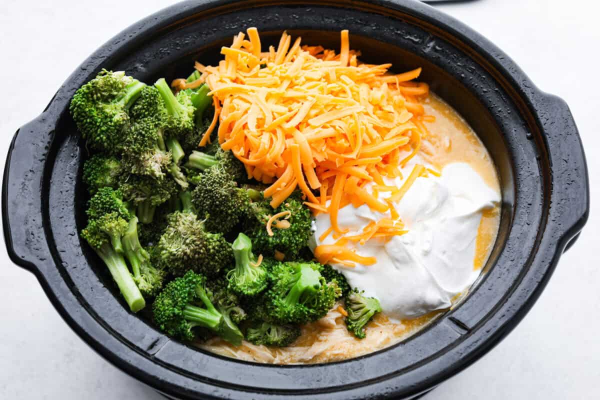 Overhead shot of broccoli, cheese and sour cream over the top of the chicken mixture. 