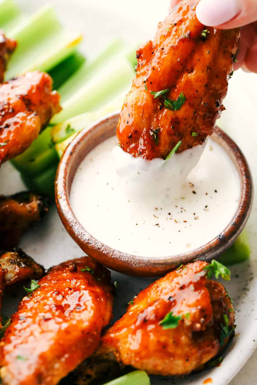 Dipping a chicken wing in ranch sauce.
