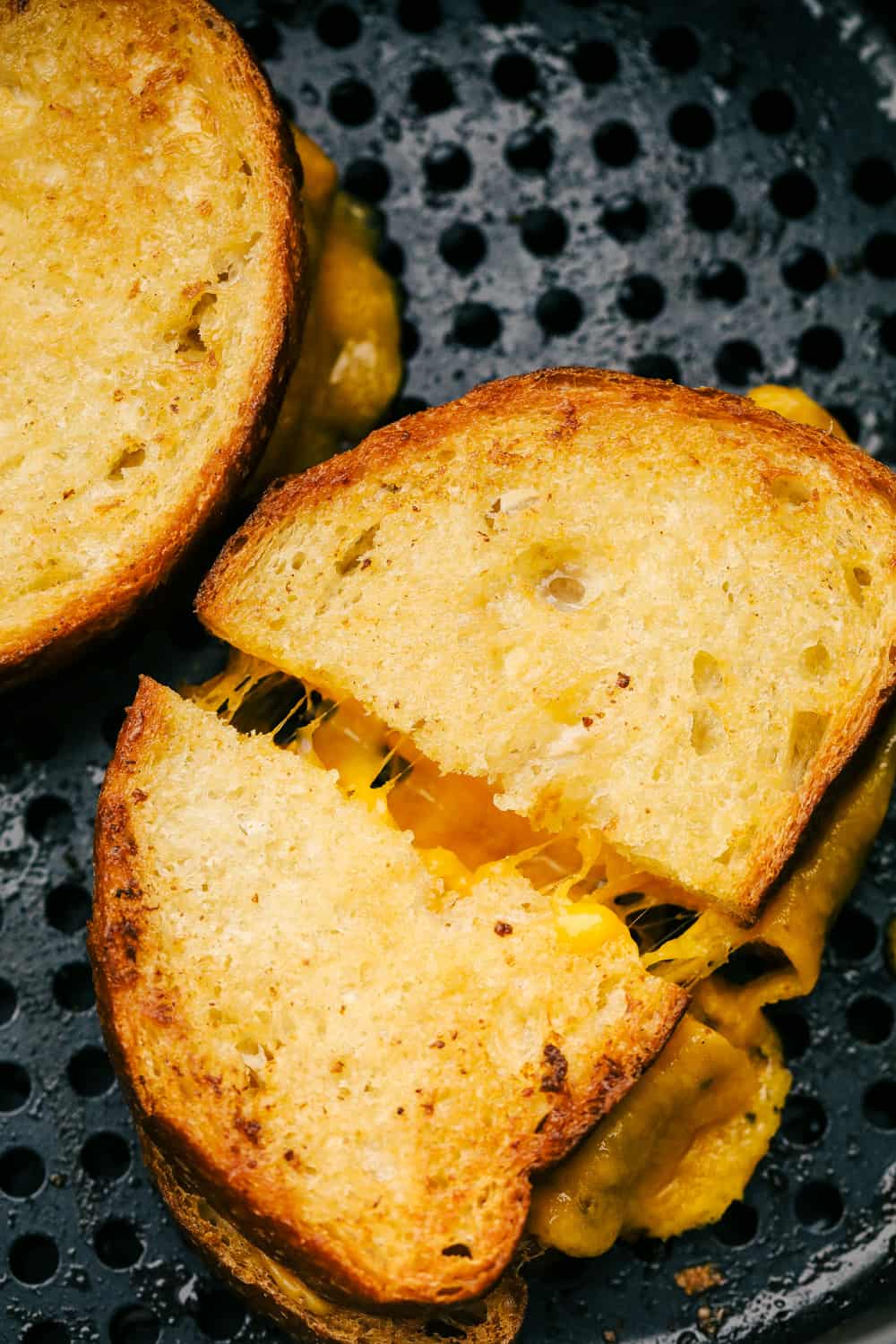 Fourth photo of grilled cheese cut in half in the air fryer basket.