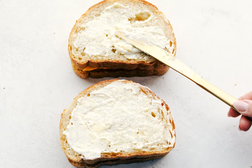 Buttering the back of grilled cheese sandwich before air frying. 