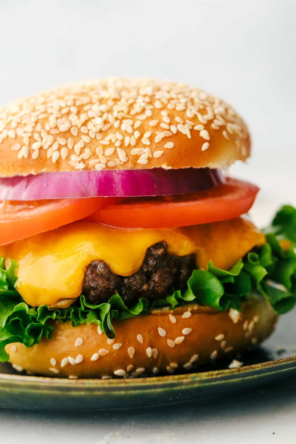 Perfect juicy air fryer hamburger on a bun with cheese, tomato, lettuce and onion. 