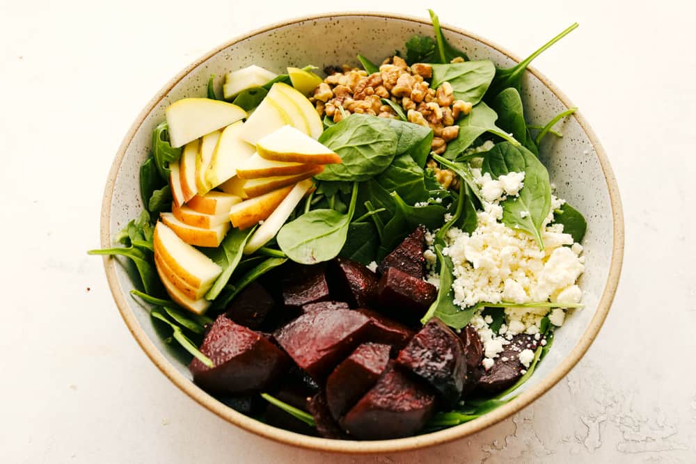 Pears, beets, spinach, feta and nuts in a bowl. 