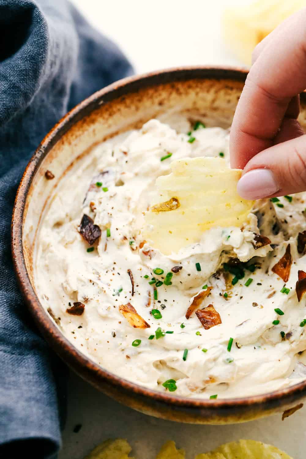 Dipping chips into the Best French Onion Dip.