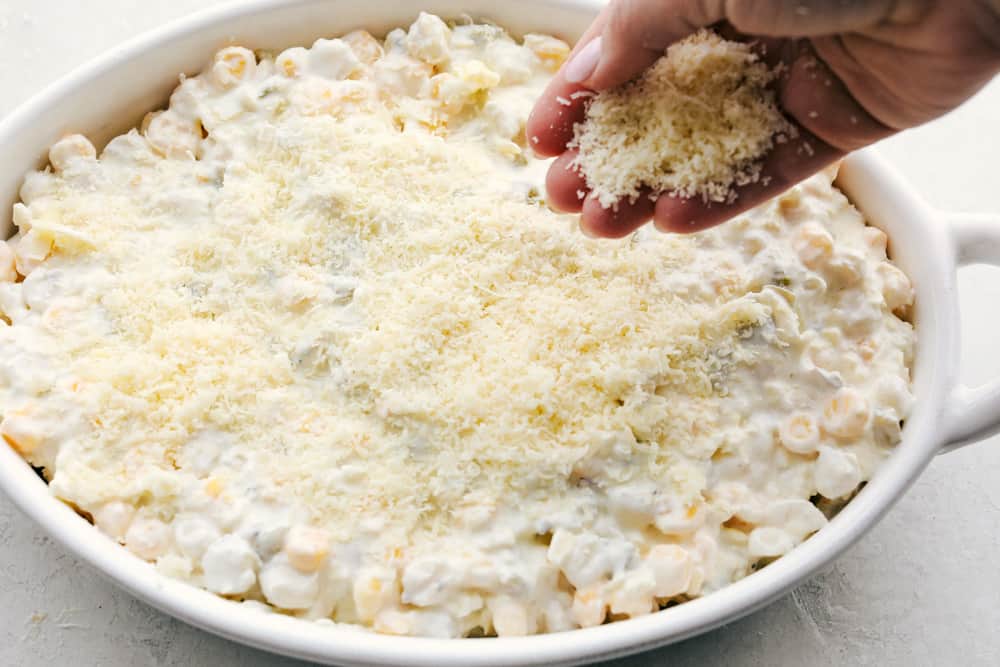 Putting the cheese topping on top of hominy casserole.