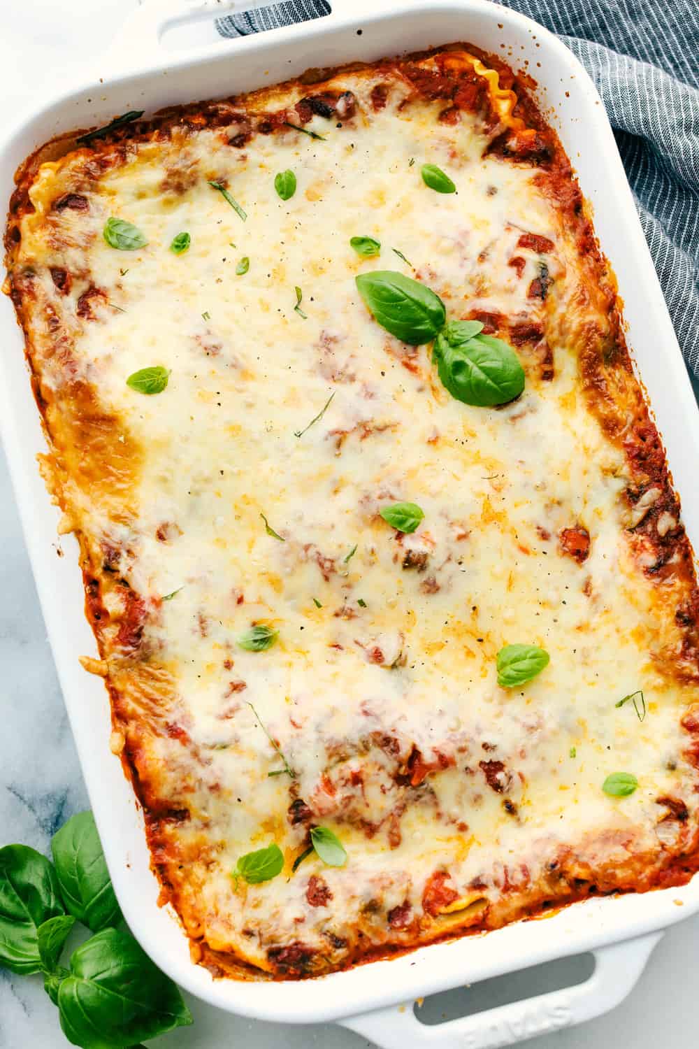 Vegetable Lasagna in a white dish with basil on top. 