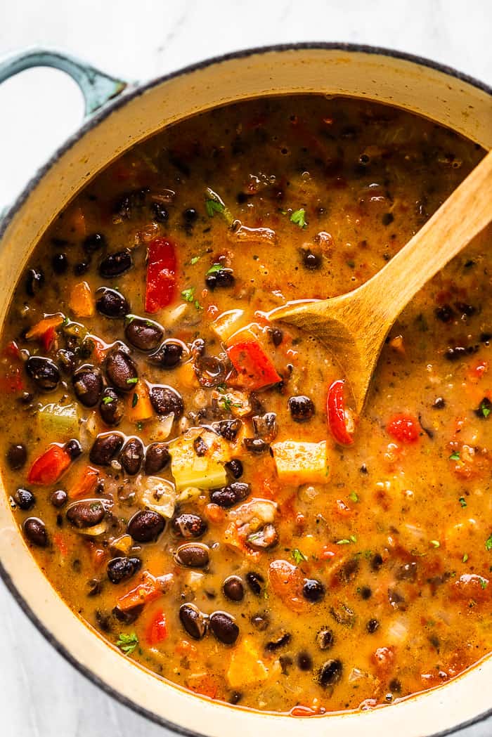 A pot of black bean soup with a wooden spoon.