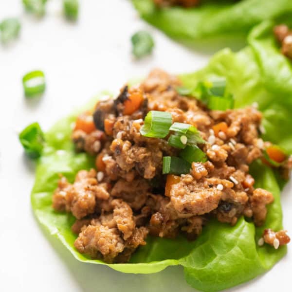 Closeup of a chicken lettuce wrap topped with spring onions