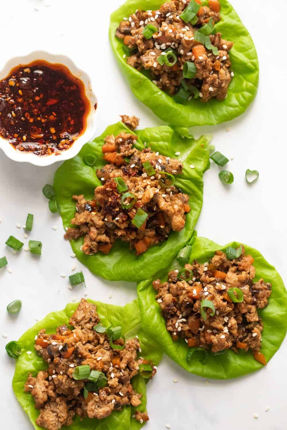 Overhead picture of chicken lettuce wraps with sweet chilli sauce on the side