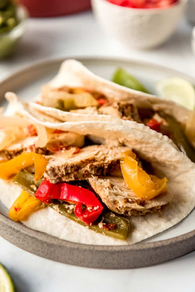 Crockpot chicken fajitas on tortillas on a plate.