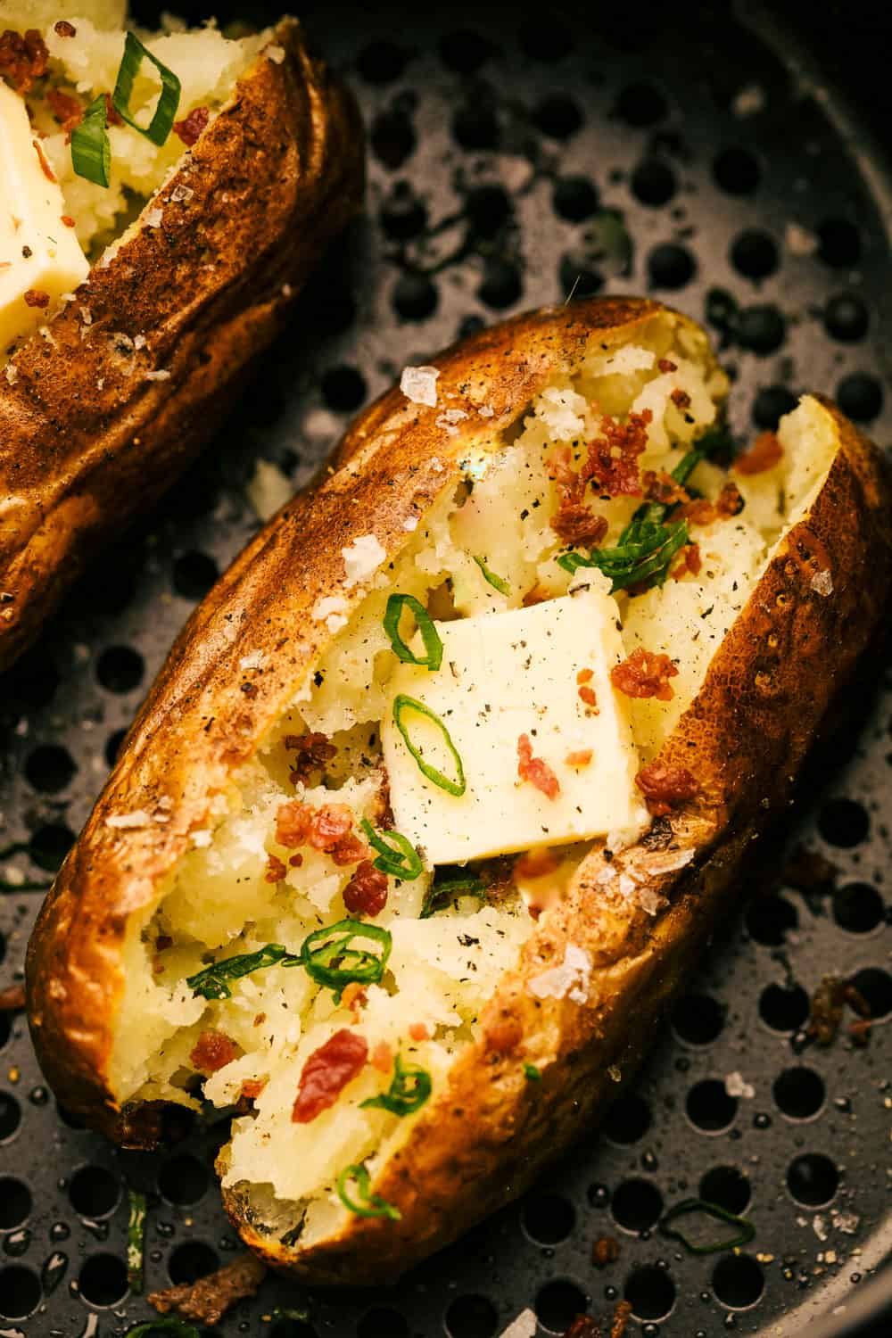 Air fryer baked potatoes with butter, bacon and chives. 