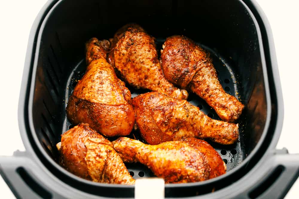 Pernas de frango prontas para cozinhar no cesto da fritadeira de ar. 