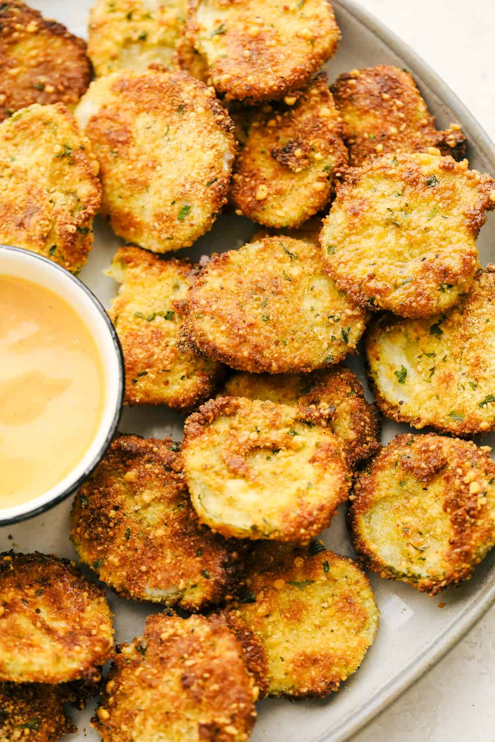 Air Fryer fried pickles with sauce on a platter. 