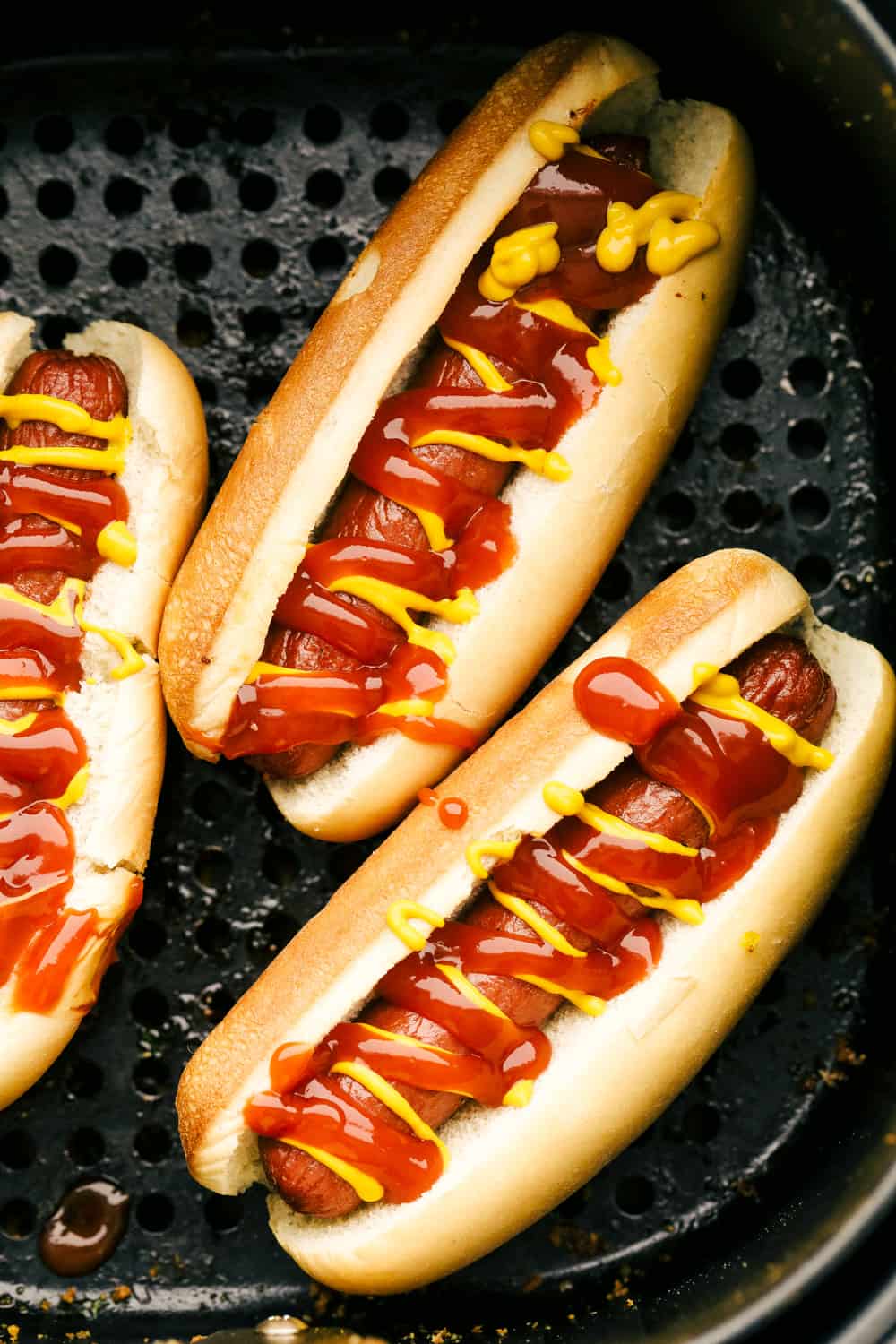 Hot dogs in buns with ketchup and mustard up close. 