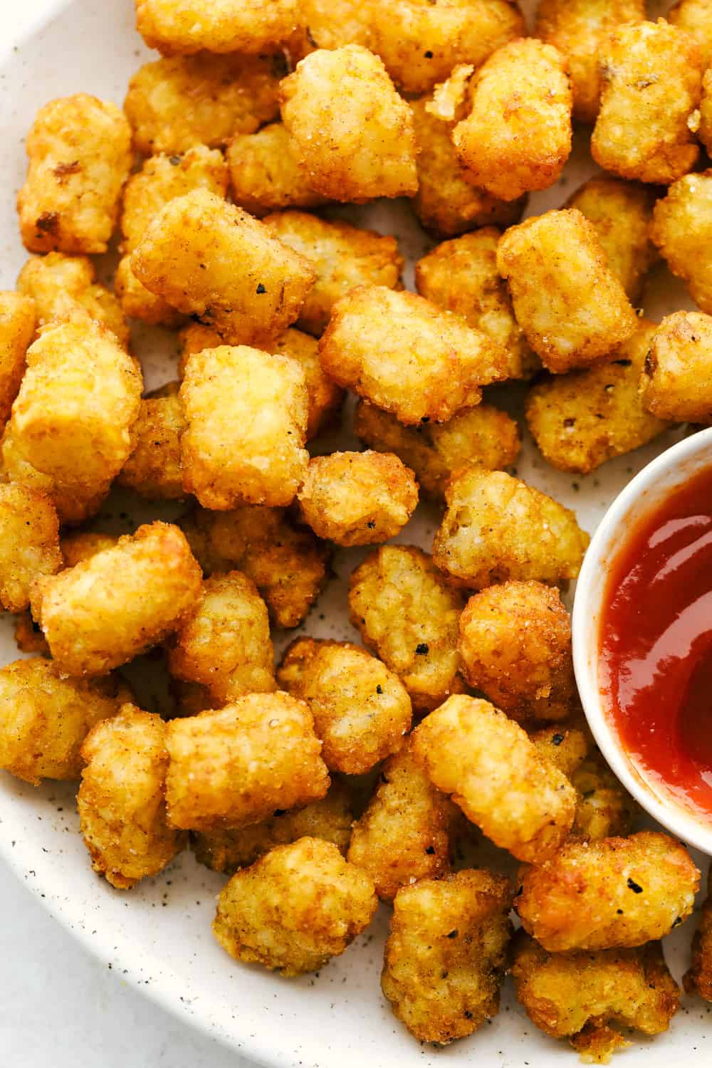 Perfect air fryer tater tots on a plate with ketchup. 