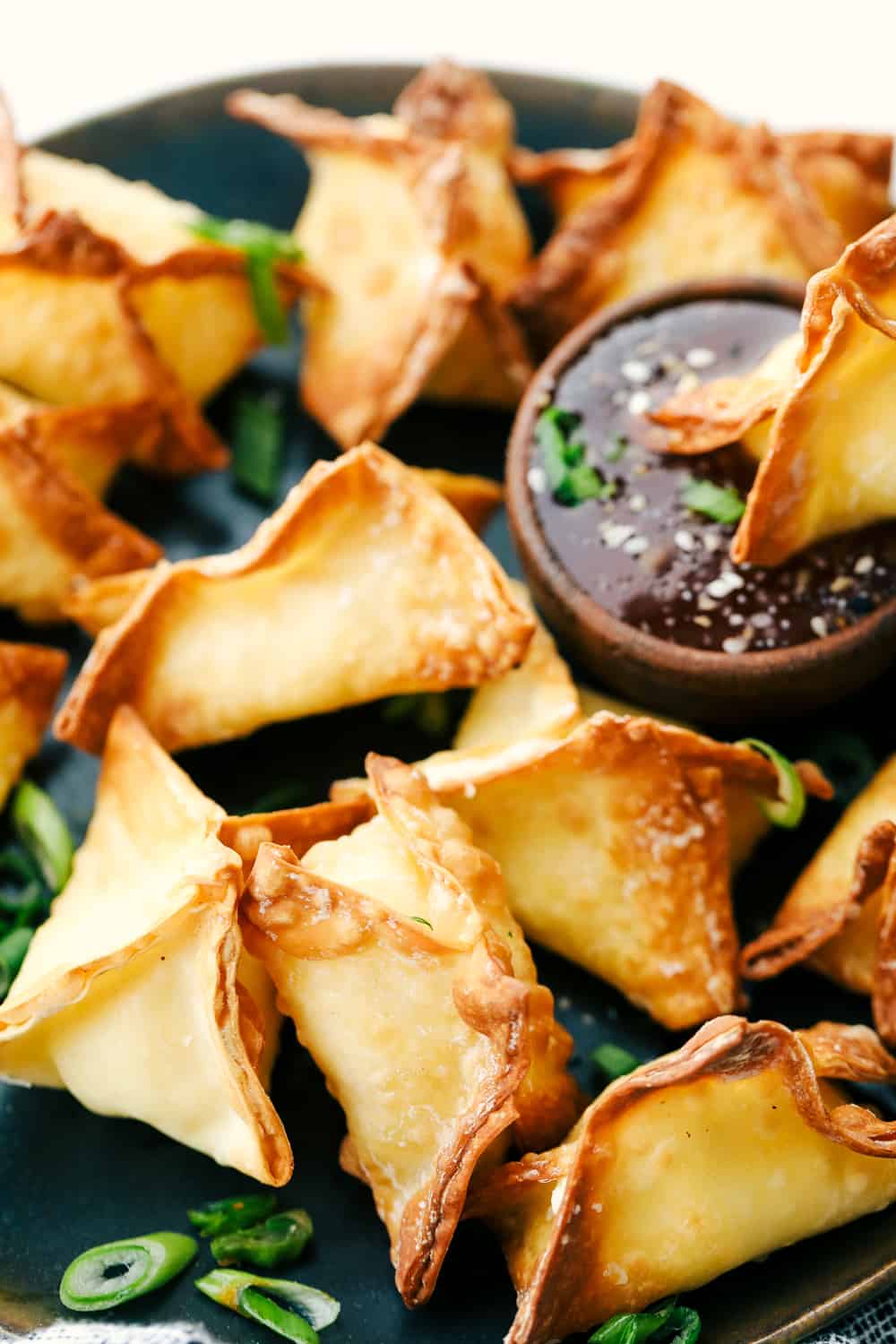 Perfectly air fried wontons on a plate with dipping sauce. 