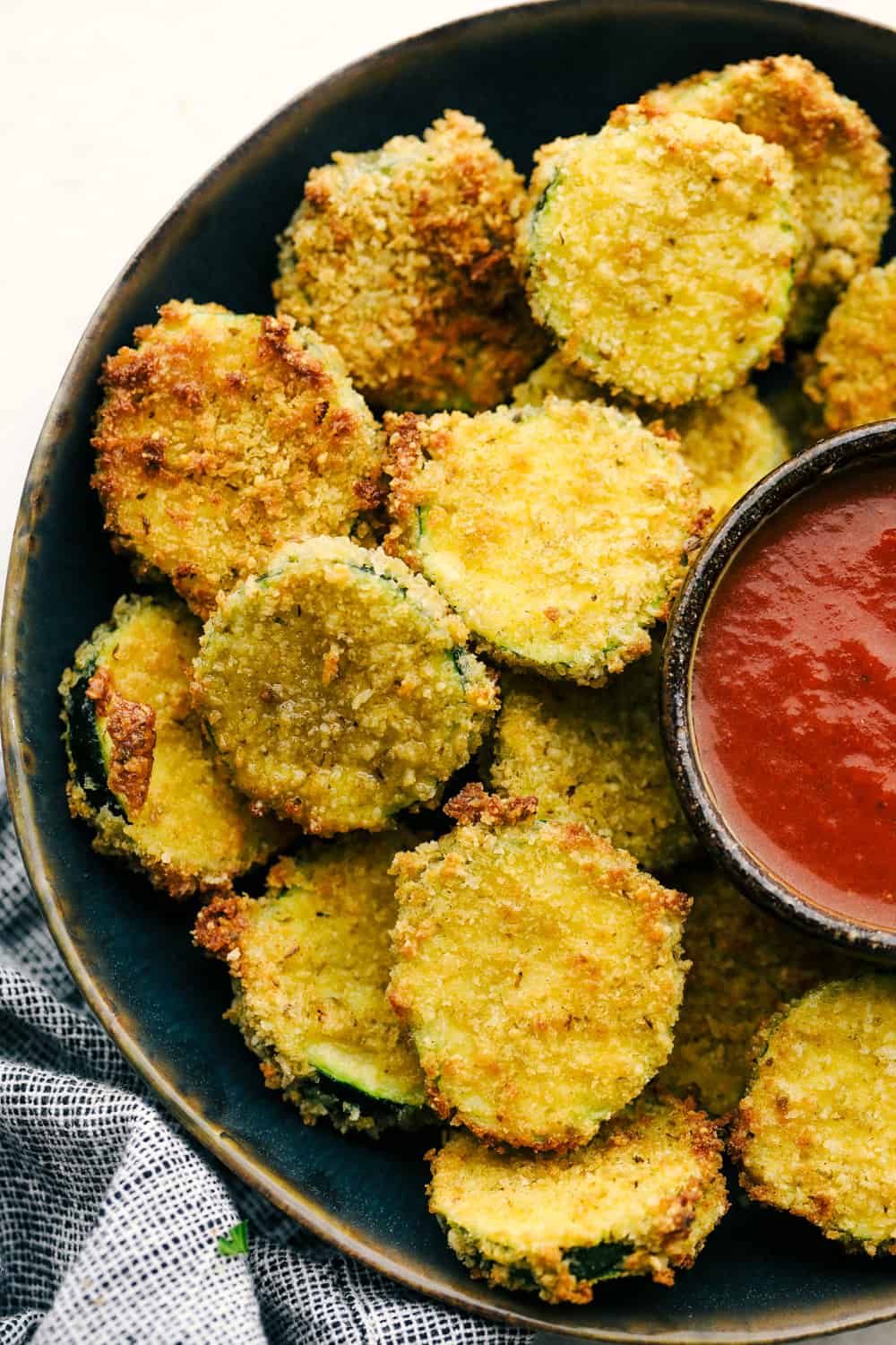 A plate for perfectly air fried zucchini chips with ketchup. 